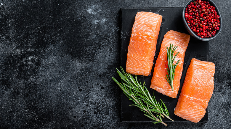 Raw salmon fillets on a black background