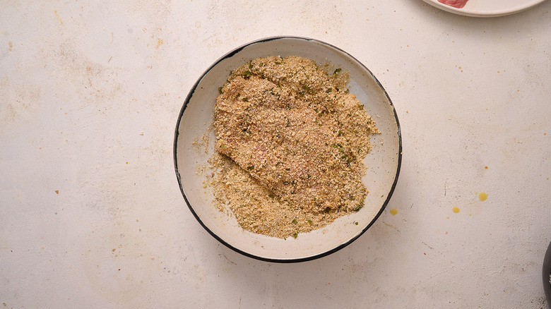 pressing veal into breadcrumbs