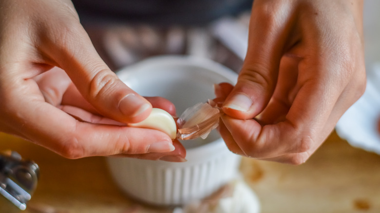 two hands peeling a garlic clove