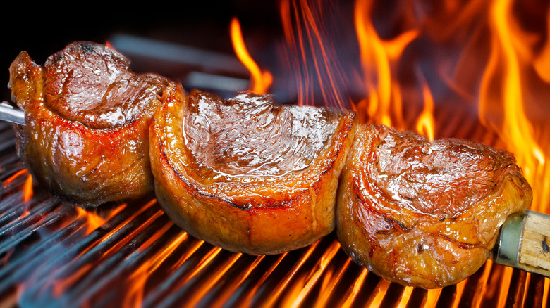 picanha on metal skewer cooking over open flame