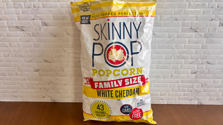 Bag of Skinny Pop popcorn in front of white tiled wall