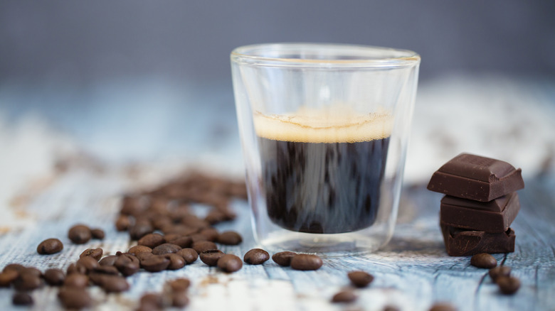 Espresso in a glass with chocolate and coffee beans on table