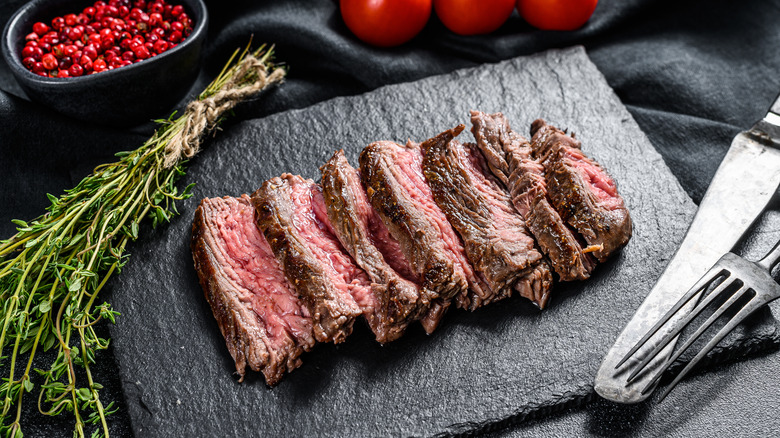 Flank steak sliced on a black serving platter