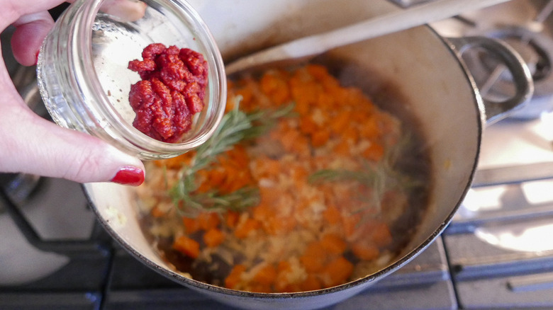 adding tomato paste to dish