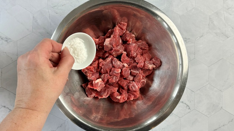 hand salting meat chunks