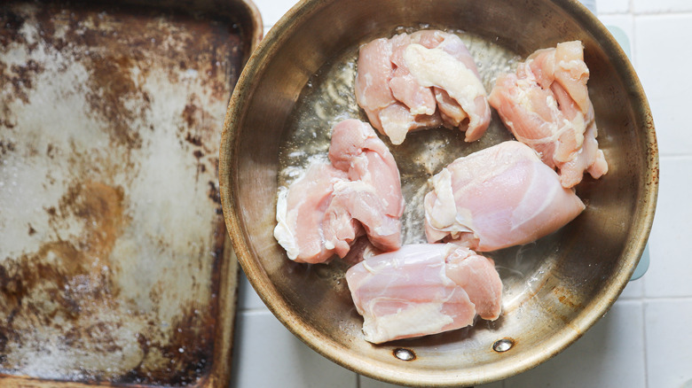 Raw chicken thighs in pan