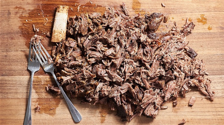 shredded beef on a cutting board