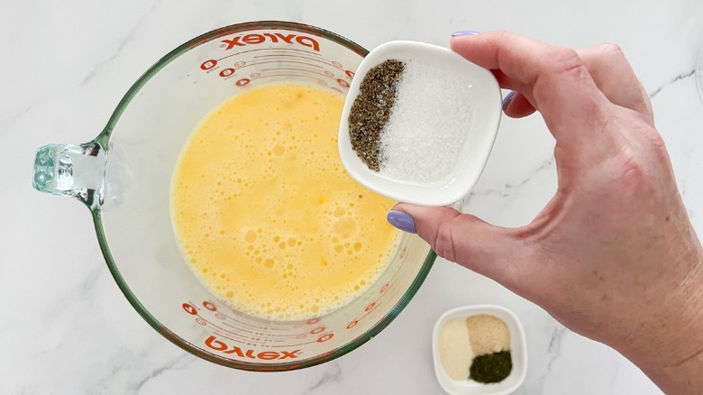 adding spices to beaten raw eggs