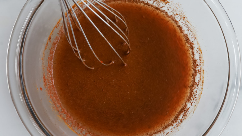 spiced broth in mixing bowl with whisk