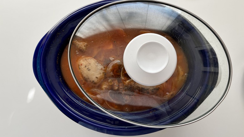 slow cooker lid at angle with cassoulet inside