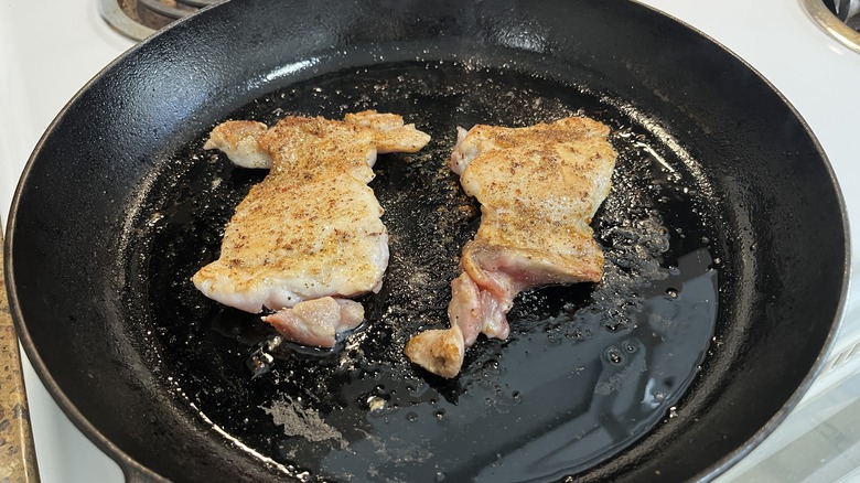 chicken thighs cooking in skillet