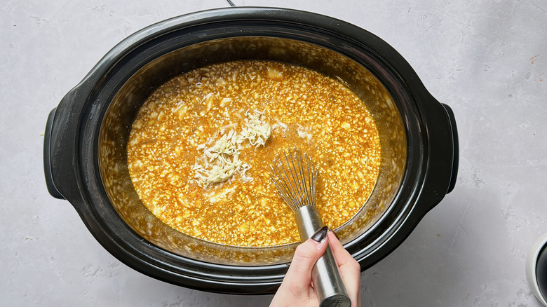 stirring cheese and chicken into soup