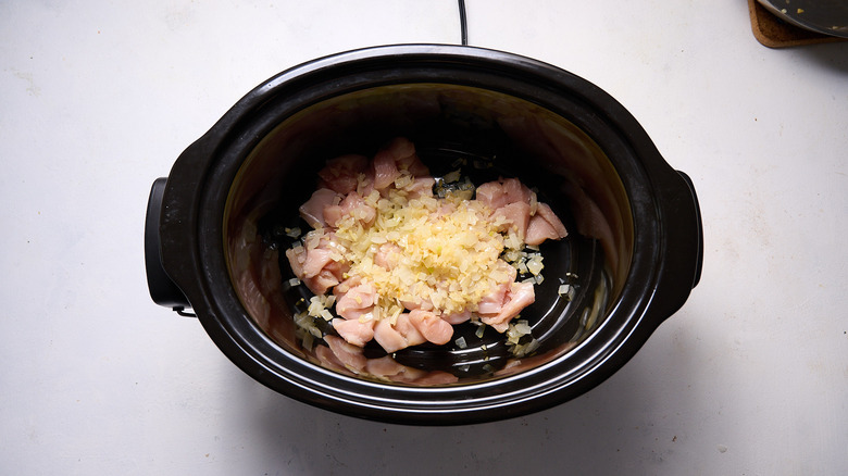 onions and chicken pieces in slow cooker
