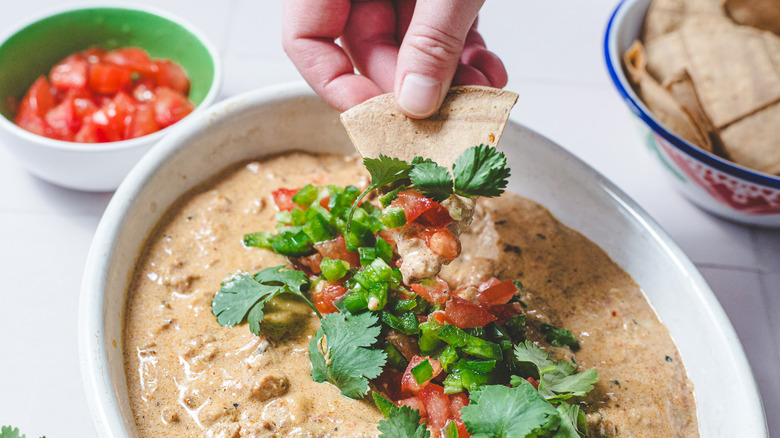 Dipping a chip into Rotel dip in baking dish