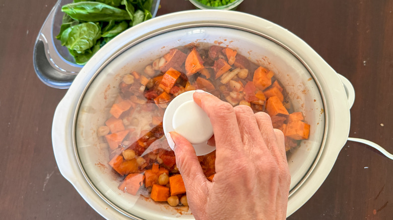 hand with slow cooker cover