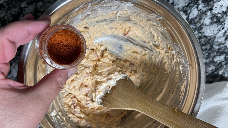 hand holding paprika over bowl