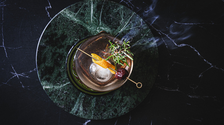 Overhead view of cocktail with smoking rosemary branch