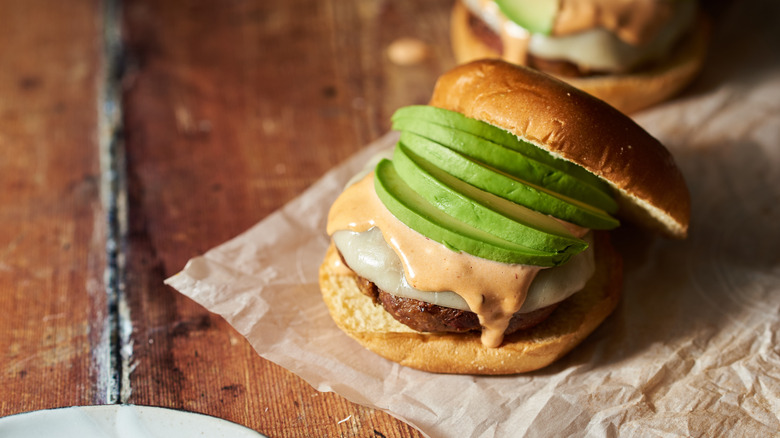 burger with avocado on table