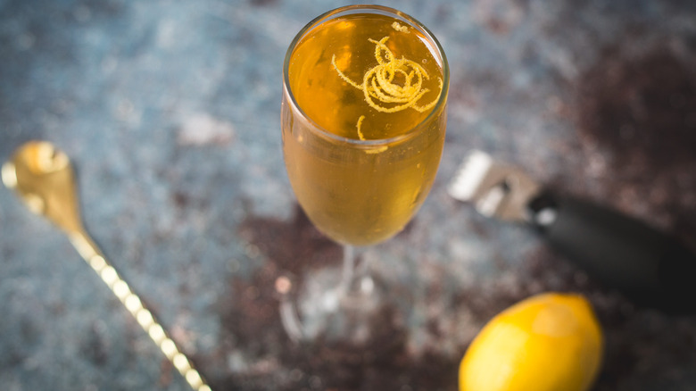 Overhead view of cocktail glass with spoon, peeler and lemons