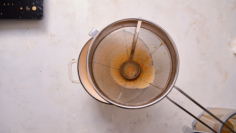 straining soup in a chinois