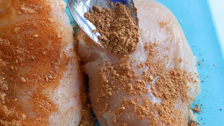 raw chicken being seasoned with taco seasoning