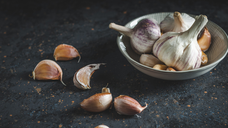 Garlic heads and garlic cloves scattered on a surface.