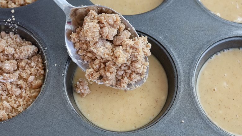 spooning crumble into muffin tin