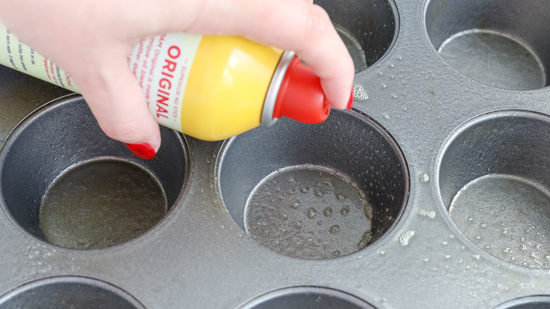 spraying cooking spray on muffin tin