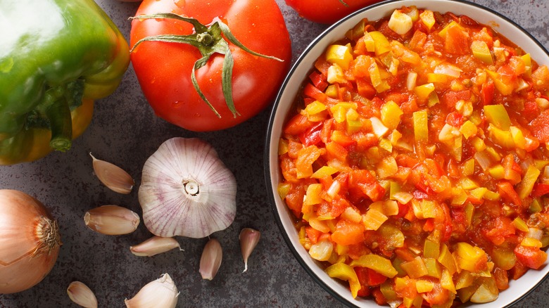 sofrito in a bowl with tomatoes next to ingredients