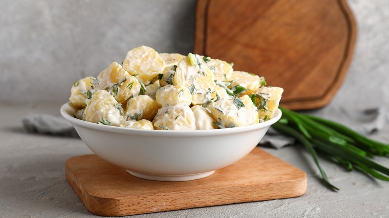 Potato salad in bowl on wood board 