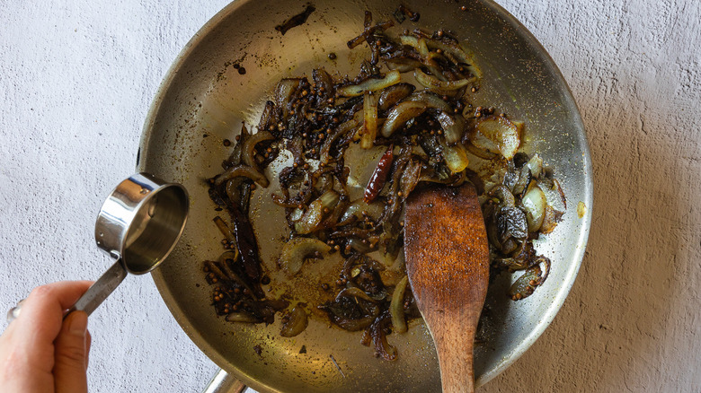 Adding water to pan with onions