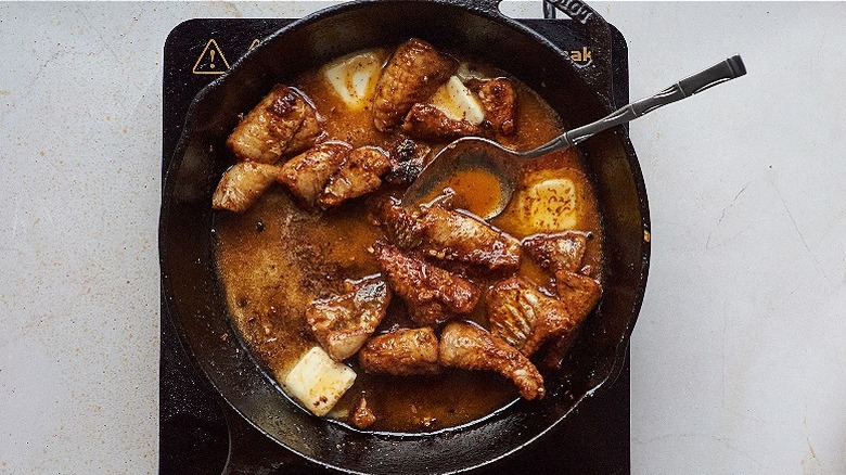 stirring butter into catfish in skillet