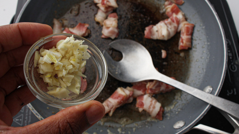 hand holding garlic over bacon
