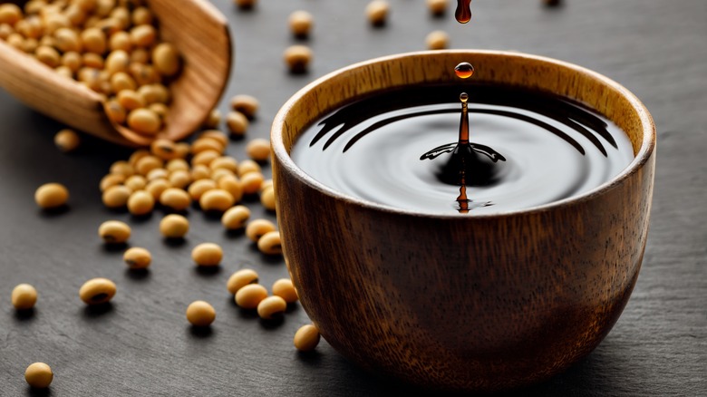 bowl of soy sauce surrounded by soy beans