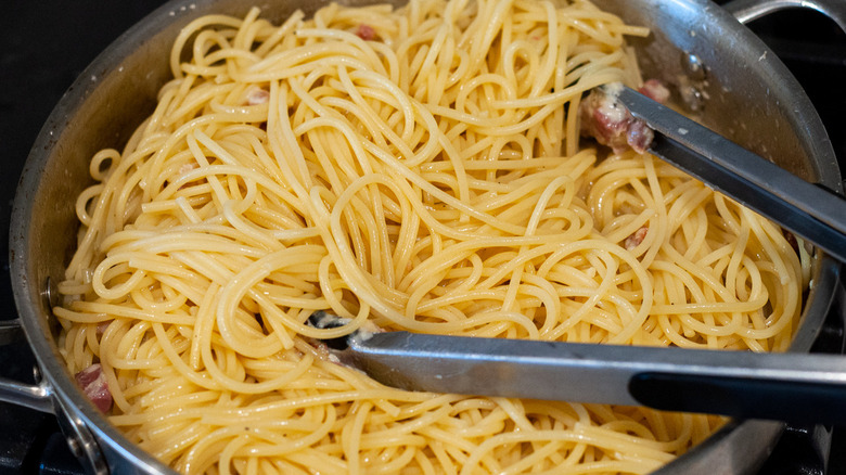 spaghetti in pan with tongs