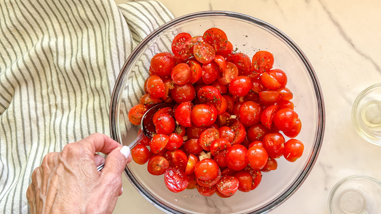 hand with spoon and tomatoes