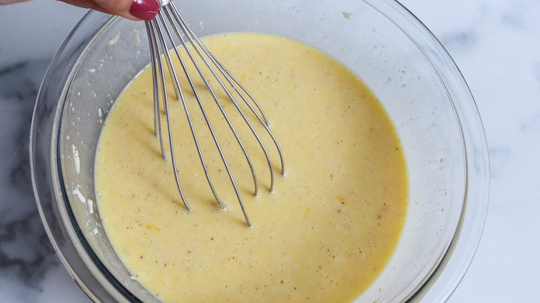 hand mixing eggs in bowl