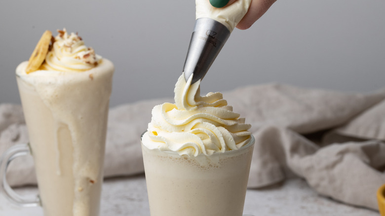 piping whipped cream onto a milkshake 
