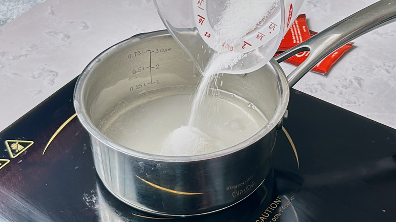 adding sugar to a saucepan