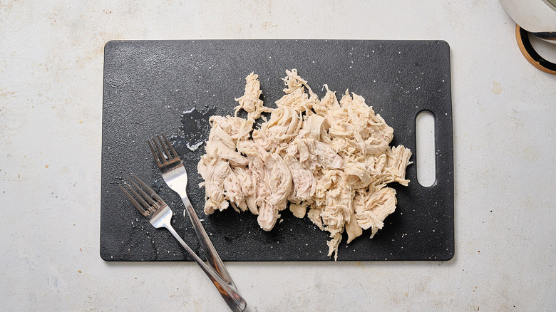 shredding chicken on cutting board