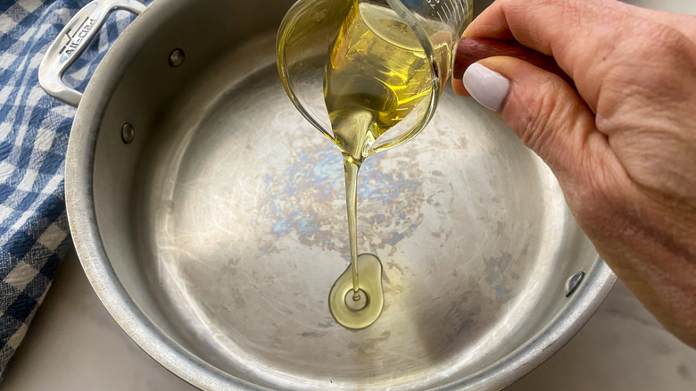 hand adding oil to pan