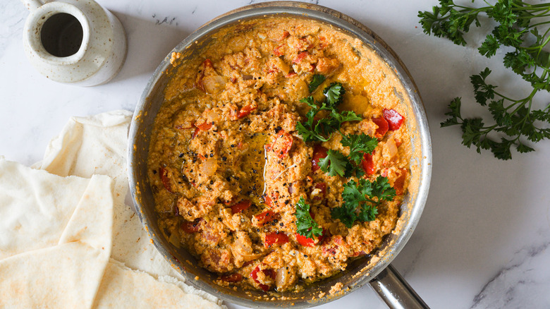 Turkish eggs in pan with parsley and pitas