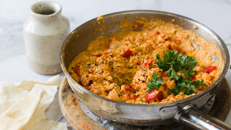 Turkish eggs in pan with parsley, pepper and olive oil