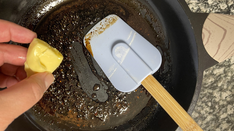 hand adding butter to pan