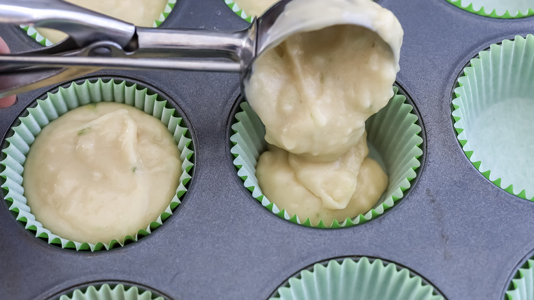 cupcake pan with batter being scooped into it