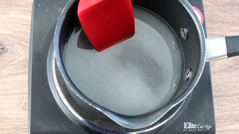 a saucepan on a burner with sugar and water in it