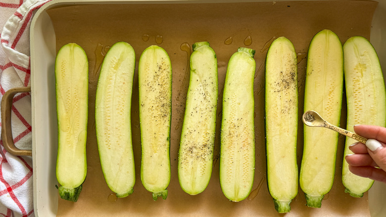 hand adding pepper to zucchini