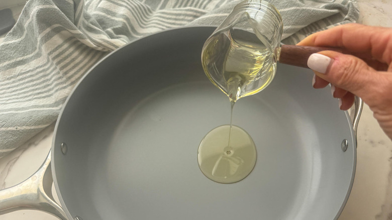 hand adding oil to a pan