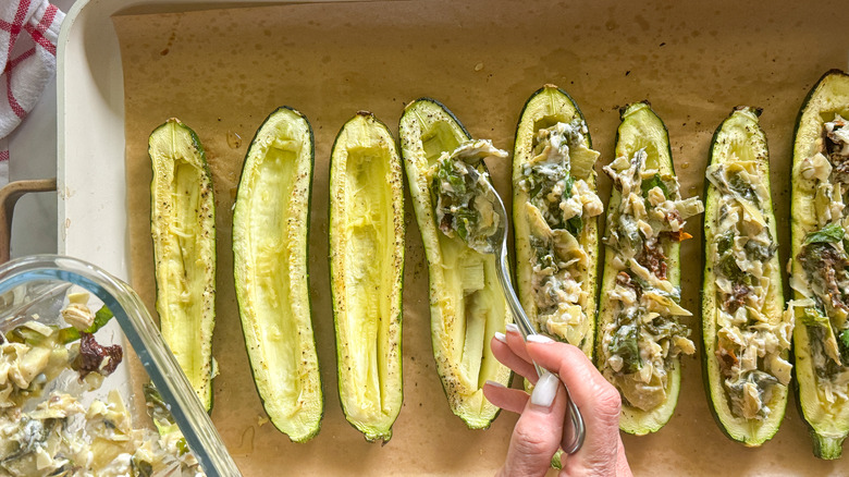 hand stuffing zucchini with mixture