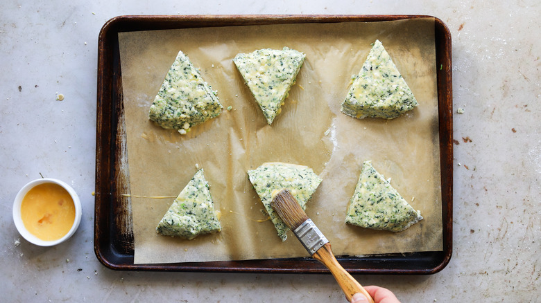 Hand brushing egg onto unbaked scones